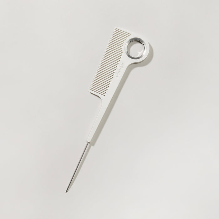 Cécred rat tail comb laid flat on a light surface highlighting fine-tooth design.