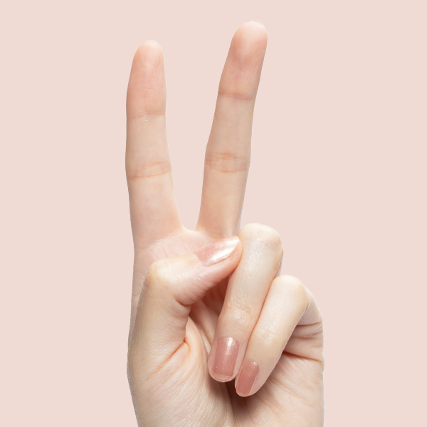 Hand with short nails in shimmery Cookie Swap polish making a peace sign on soft beige background