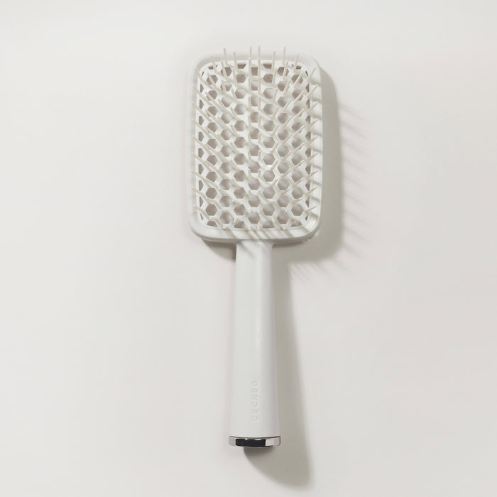 Flat lay of Cécred Detangling Brush highlighting its clean silhouette and design details from handle to head.